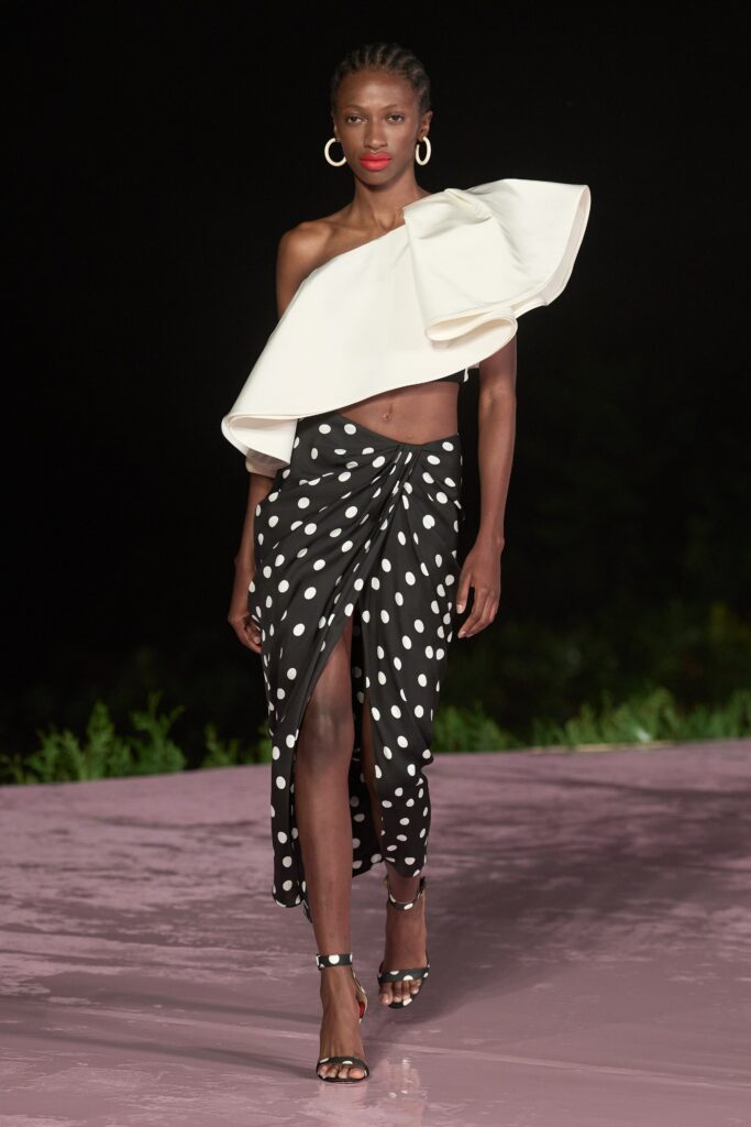 A fitted top with an asymmetric design paired with a black polka-dot skirt featuring a slit.