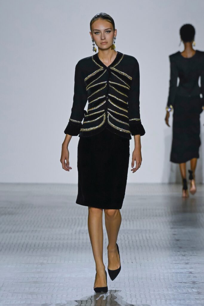 A fitted black cotton dress with long sleeves and a collared neckline in a pencil silhouette.