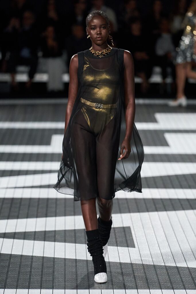 A fitted black sheer dress with a V-neckline and layered design details.
