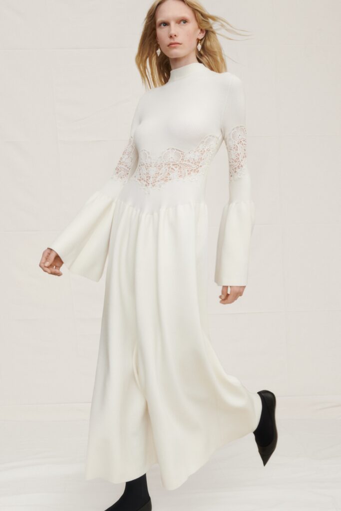 A fitted white silk long-sleeve dress with a high neckline and flared sleeves.
