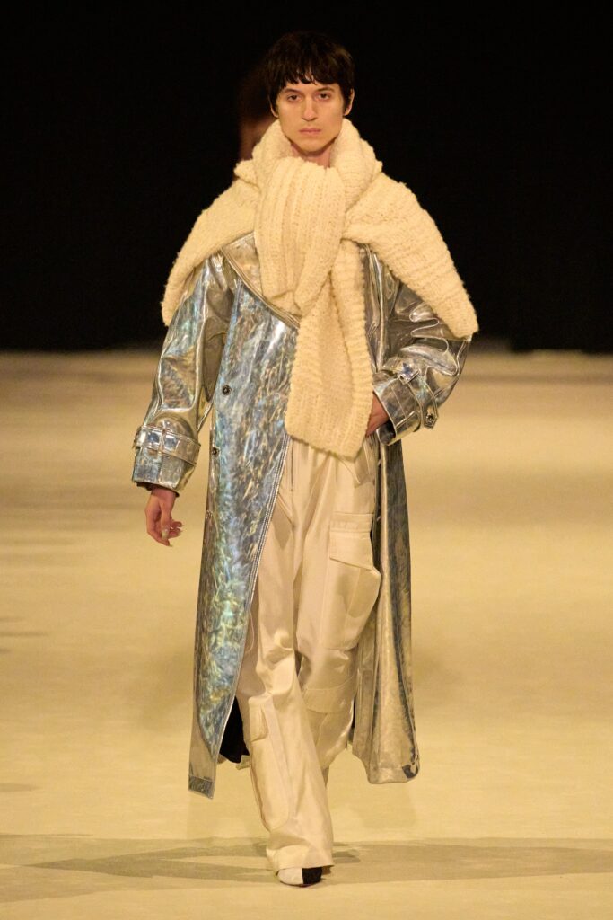 A relaxed silver silk coat paired with white pants, featuring a collared design and layered details.