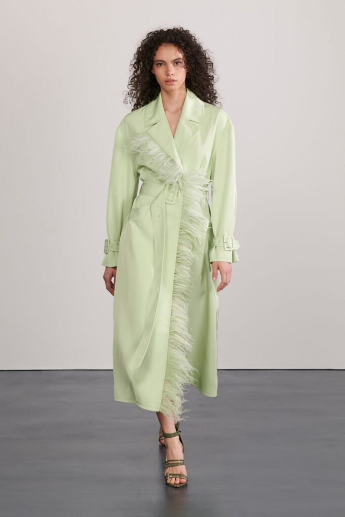 A fitted green silk coat with long sleeves, a collared neckline, and fringed detailing.