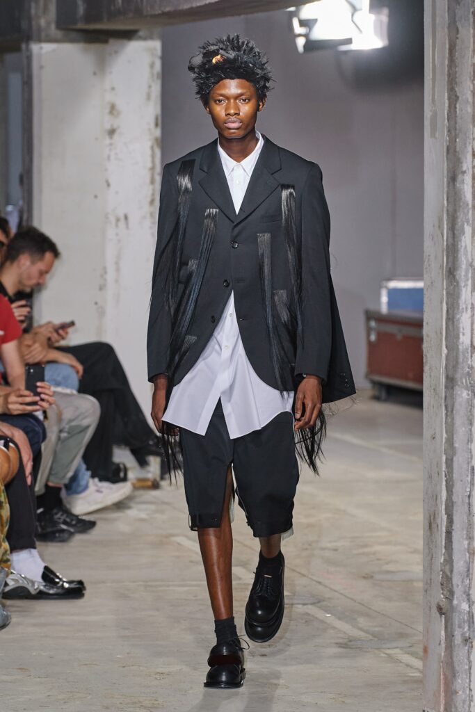 A relaxed black blazer layered over a white collared shirt with long sleeves.