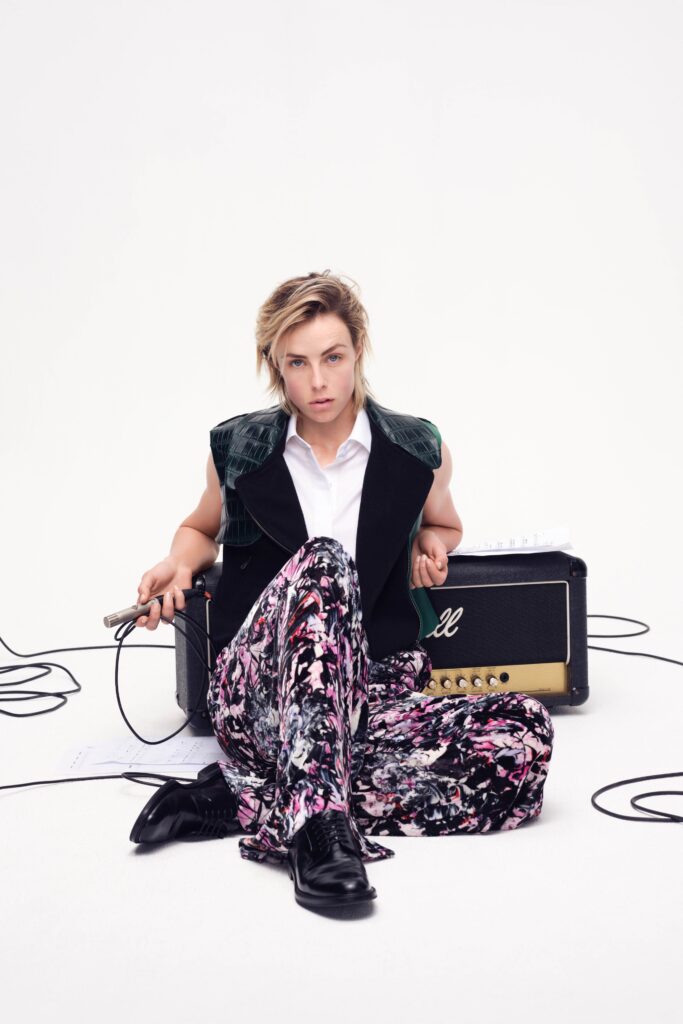 A relaxed black sleeveless vest paired with multicolor floral pants, featuring a collared shirt underneath.