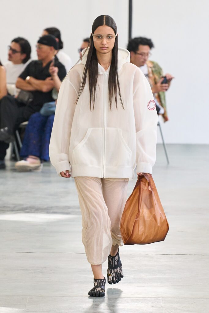 An oversized white hooded jacket paired with beige pants, creating a relaxed and layered look.