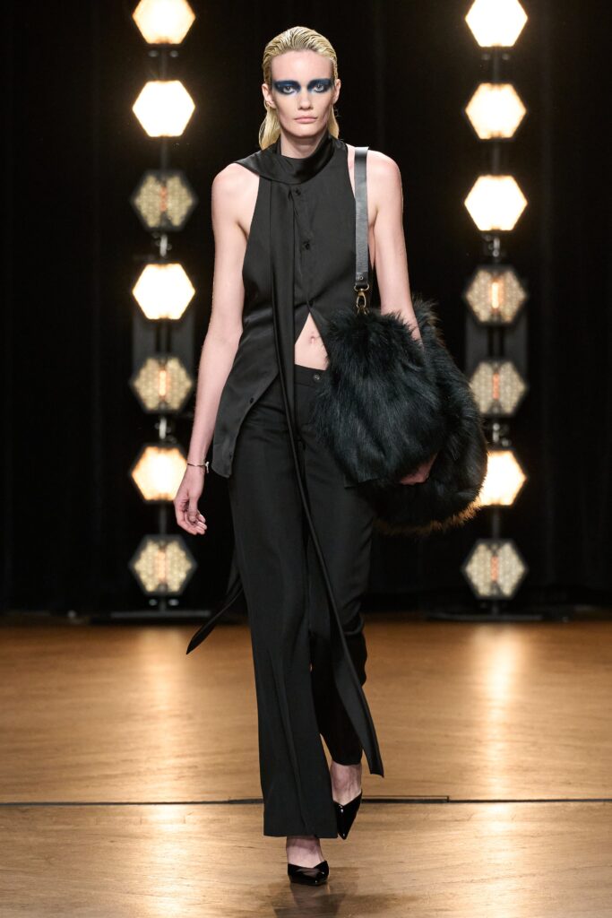 A fitted black silk jacket with an asymmetric design paired with sleek black pants.
