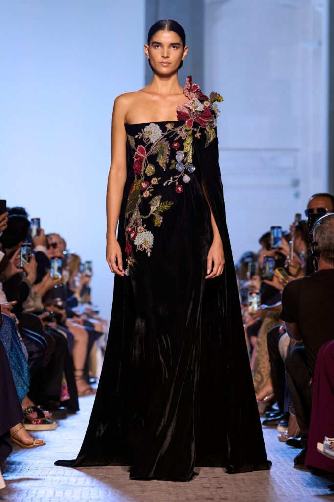 A fitted black velvet gown with a sleeveless high-neck design and intricate embroidery.