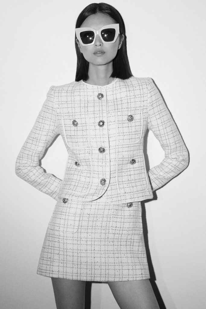 A fitted white tweed jacket with a collared design paired with a matching skirt.