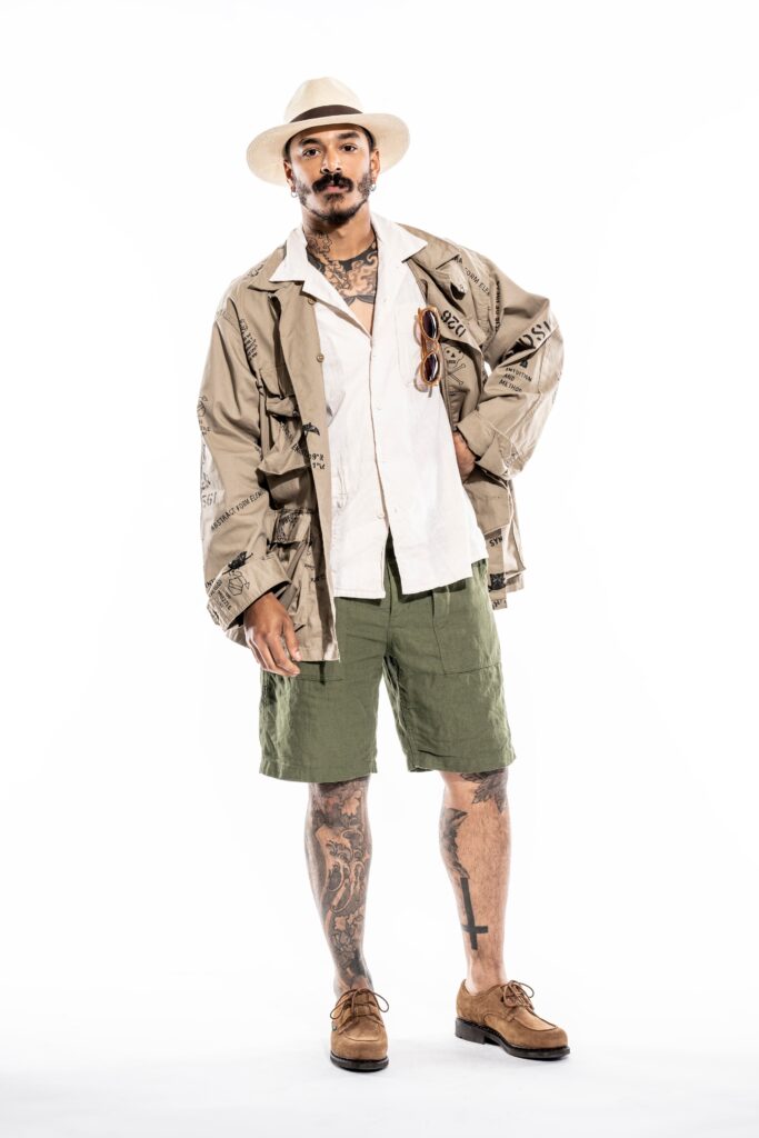 A relaxed-fit beige cotton jacket with a collared neckline paired with green shorts.