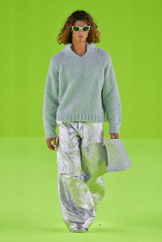 A relaxed silver knit long-sleeve sweater paired with metallic pants, creating a striking look.