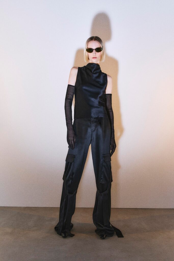 A fitted black silk sleeveless top with a high-neck and asymmetric design paired with matching pants.