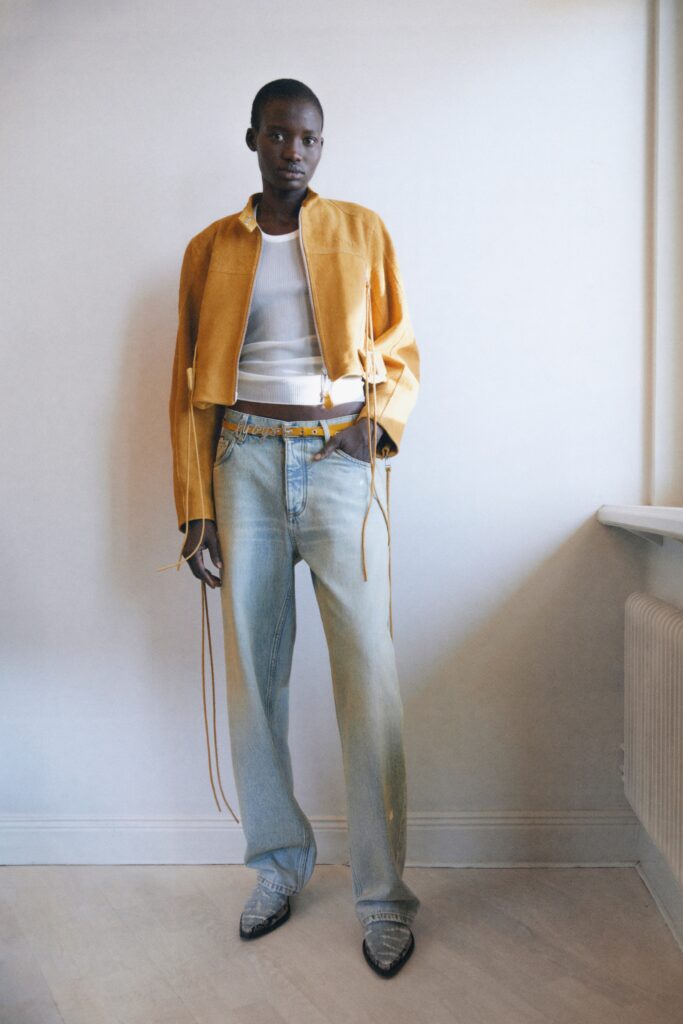 A relaxed yellow leather jacket paired with straight-leg blue denim pants.