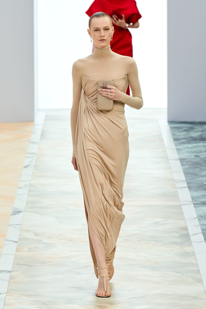 A fitted beige silk dress with a sleeveless design and draped detailing.