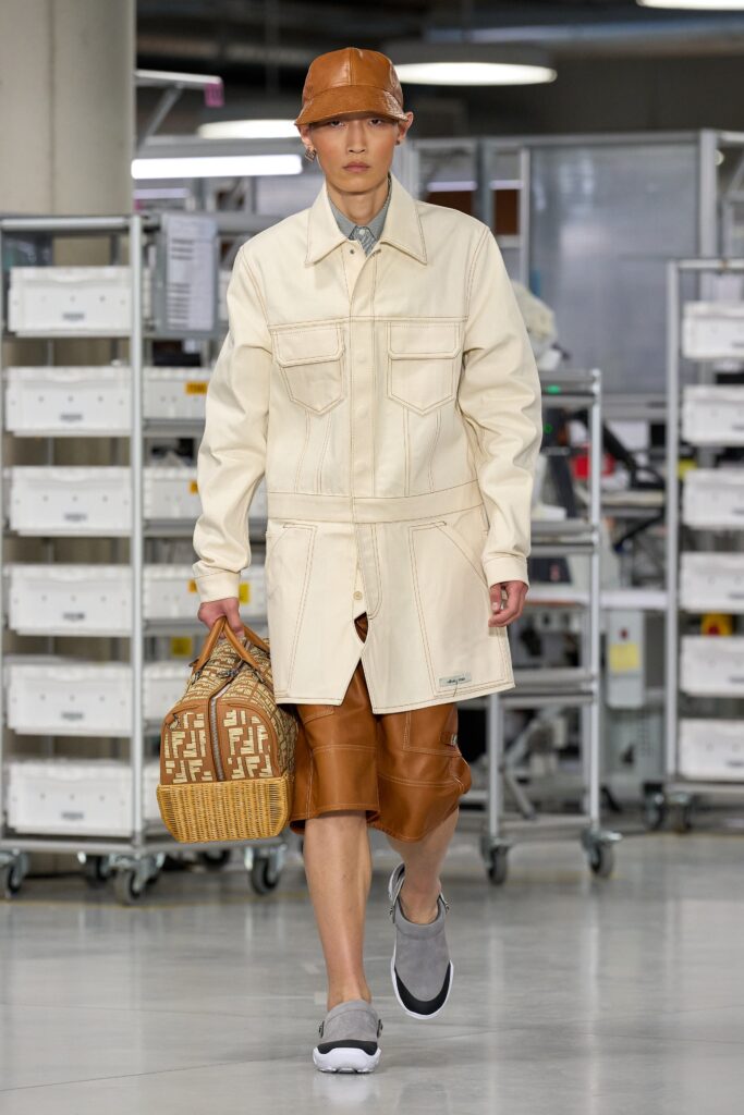 A relaxed-fit beige leather coat with long sleeves and a collared design, paired with brown shorts.