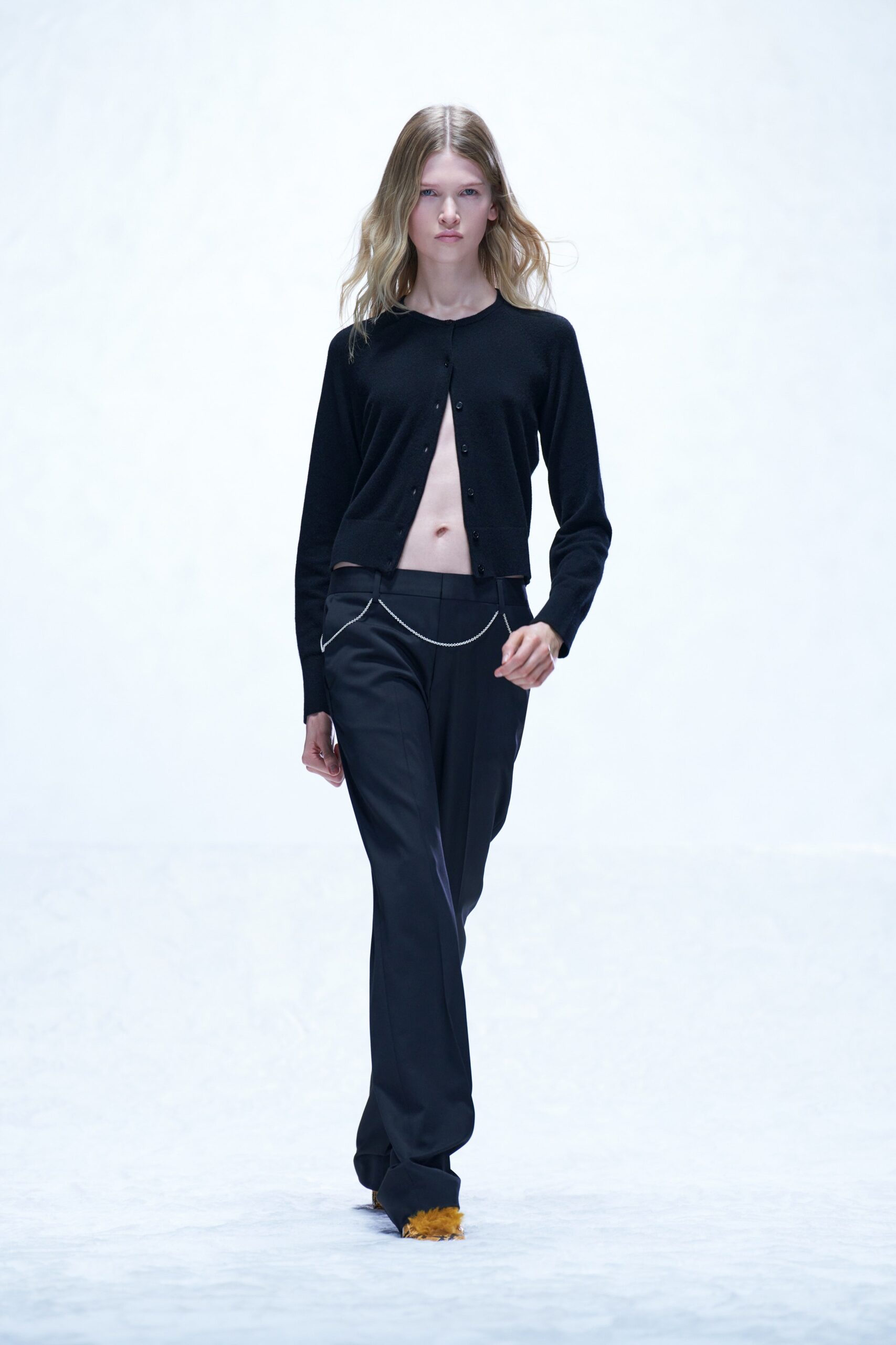 A fitted black cardigan with long sleeves paired with straight-leg black pants.