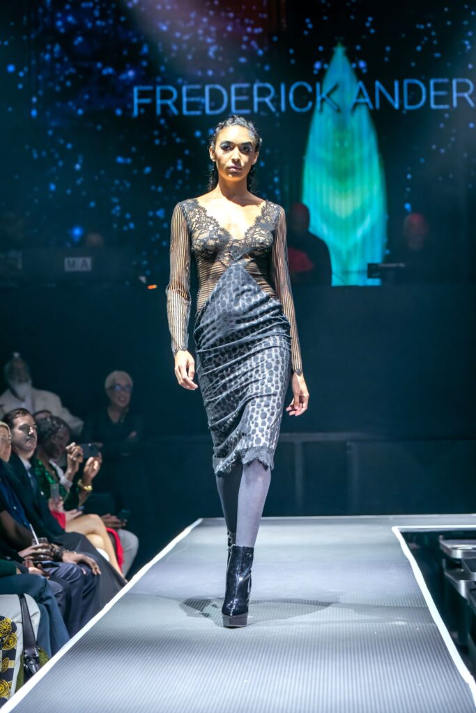 A fitted black silk dress with long sleeves, a V-neckline, and a slit detail.