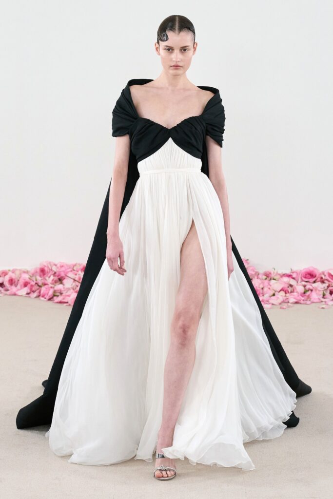 A fitted black and white silk dress with a V-neckline, asymmetric design, and a thigh-high slit.