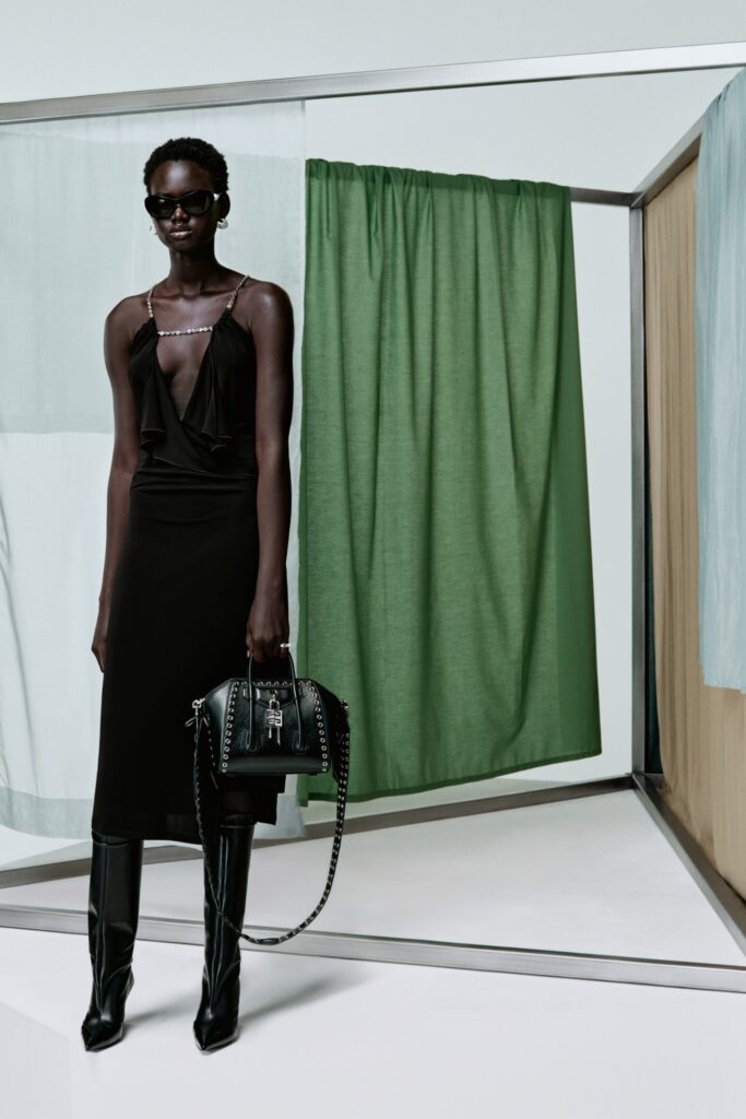 A fitted black silk sleeveless dress with a V-neckline and draped detail.