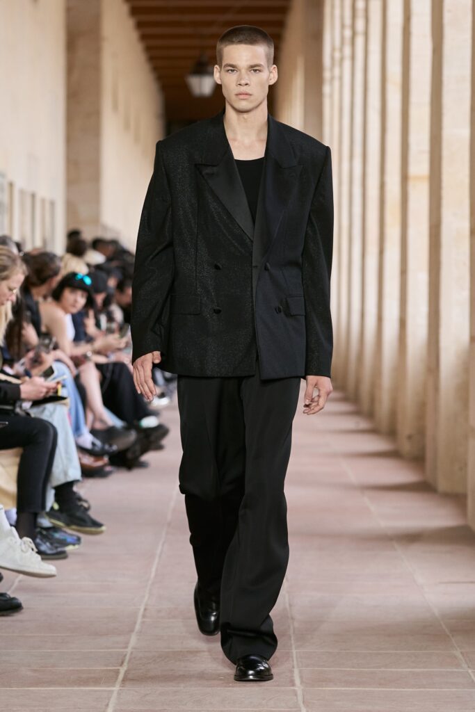 A relaxed black silk blazer with long sleeves and collared design paired with matching pants.