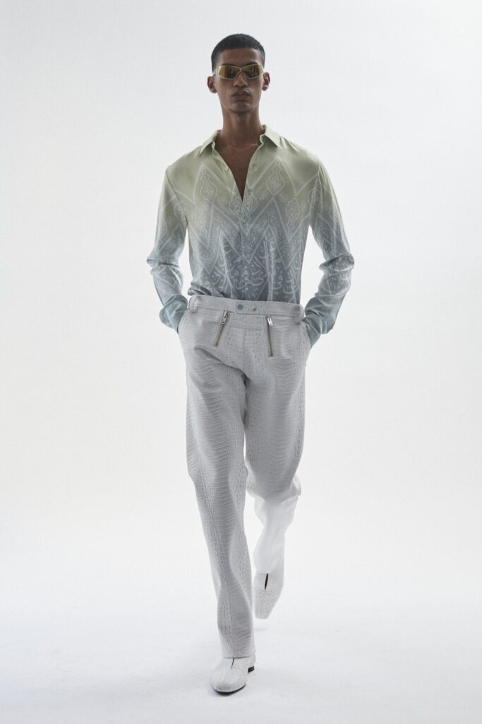 A fitted green printed long-sleeve shirt paired with slim white pants.