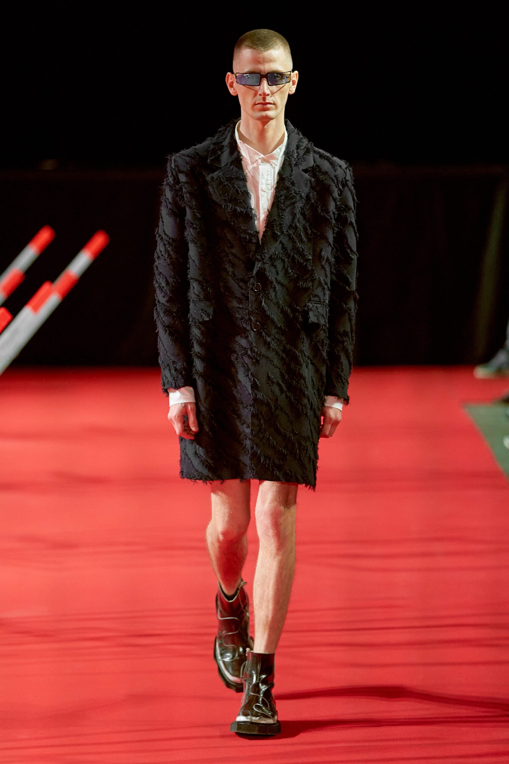 A fitted black coat dress with a textured finish and asymmetric design details.