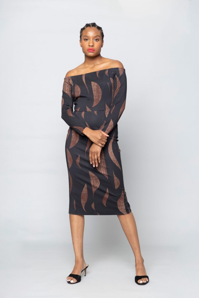 A fitted black dress with long sleeves and an off-shoulder design featuring a unique print.