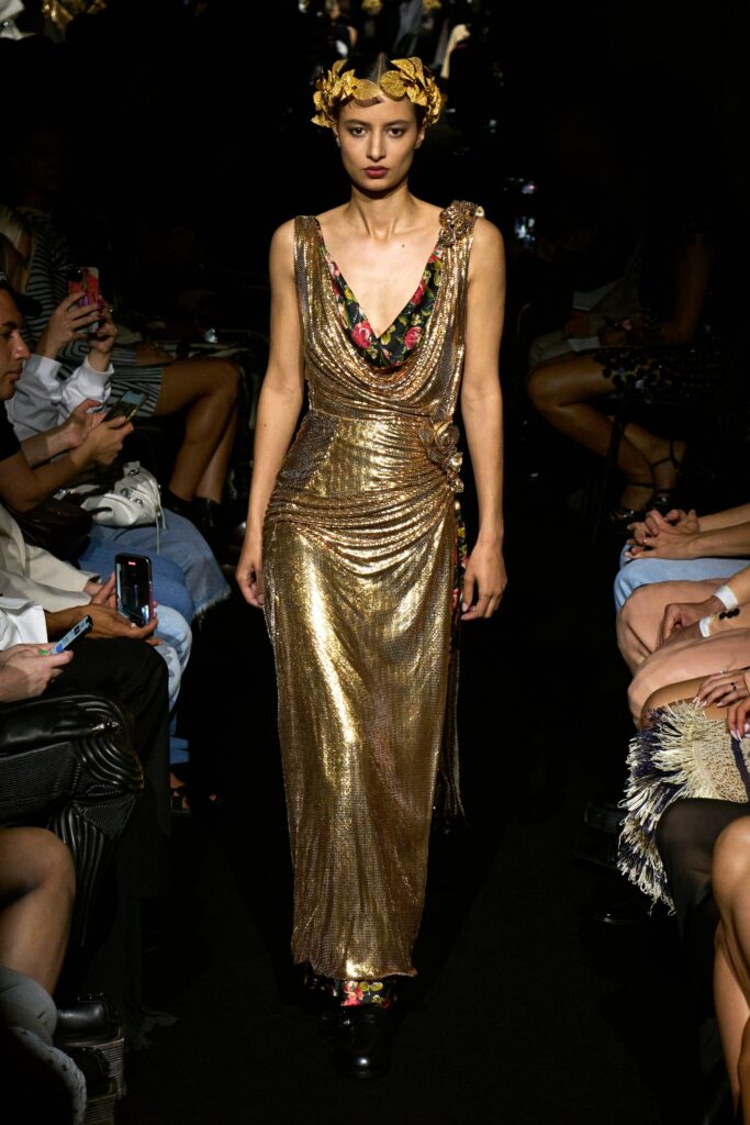 A fitted gold silk sleeveless dress with a V-neckline and draped design details.
