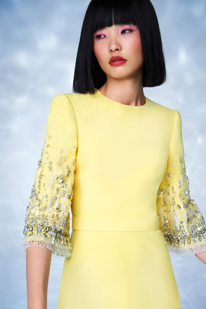 A fitted yellow silk dress with long sleeves and embroidered details.