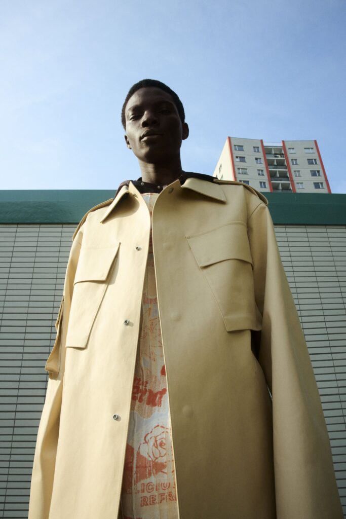 An oversized beige leather jacket layered over a printed shirt, featuring a relaxed fit.