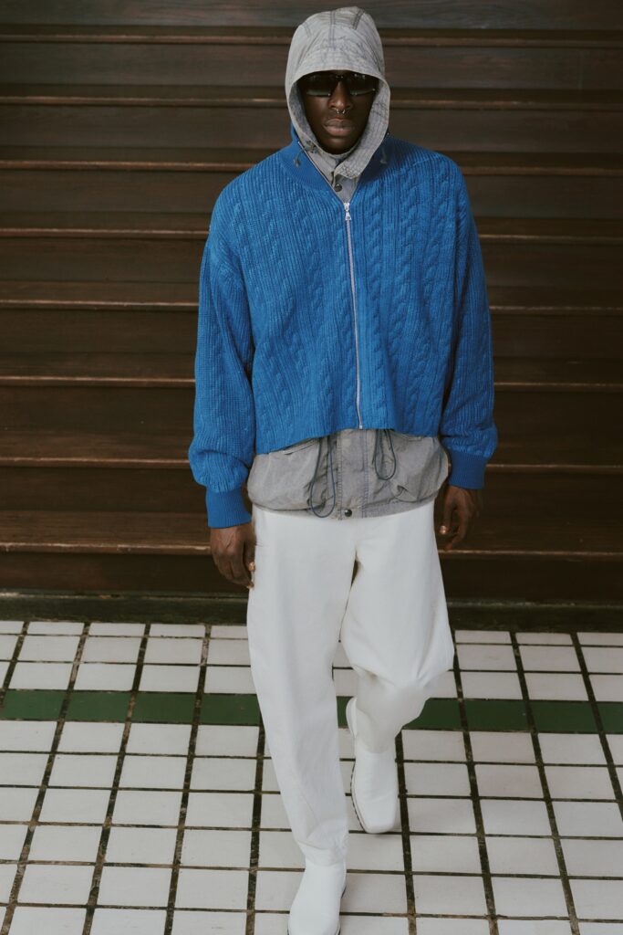 A relaxed blue hooded jacket paired with white pants, featuring a zippered design.