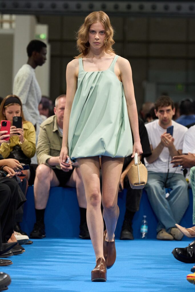 A relaxed green sleeveless dress with a high neckline and pleated design.
