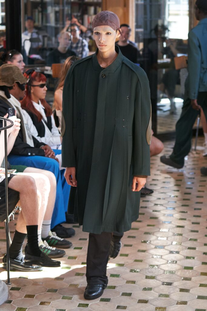 A relaxed green wool coat with long sleeves and an asymmetric design detail.