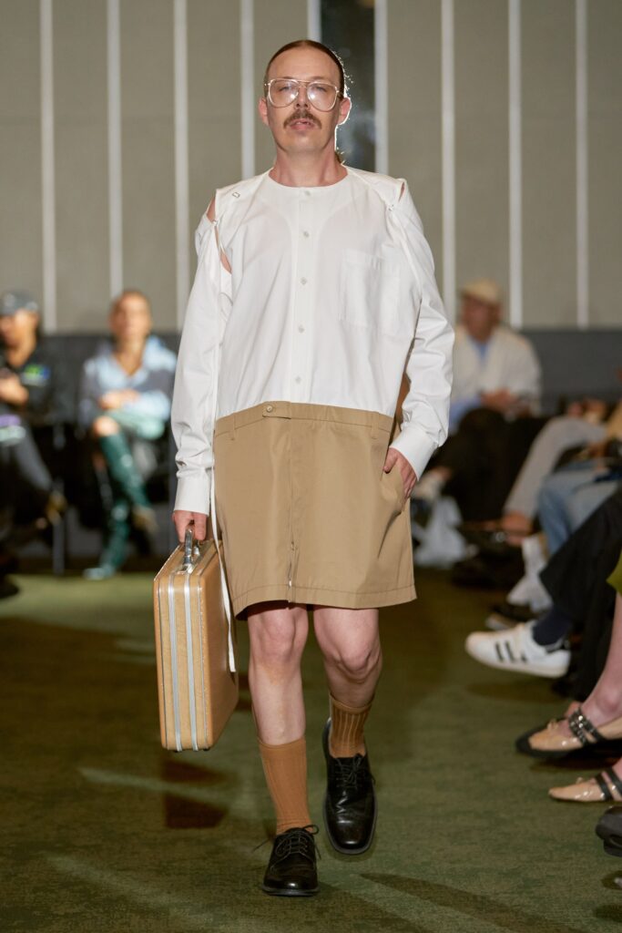 A relaxed white collared long-sleeve shirt paired with beige asymmetric shorts.