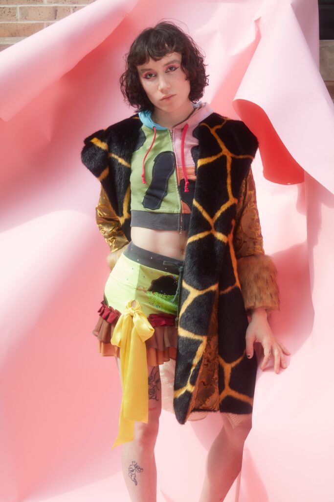 A fitted black fur coat layered over a colorful sleeveless top with an asymmetric design.