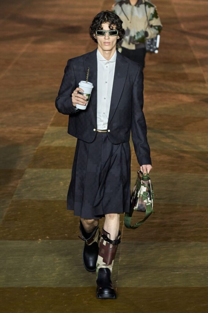 A fitted black blazer with a collared neckline paired with an asymmetric black skirt.