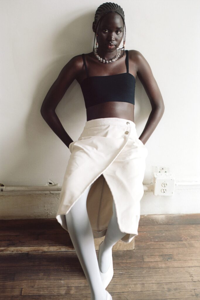 A fitted black sleeveless top paired with a high-waisted white asymmetric skirt.