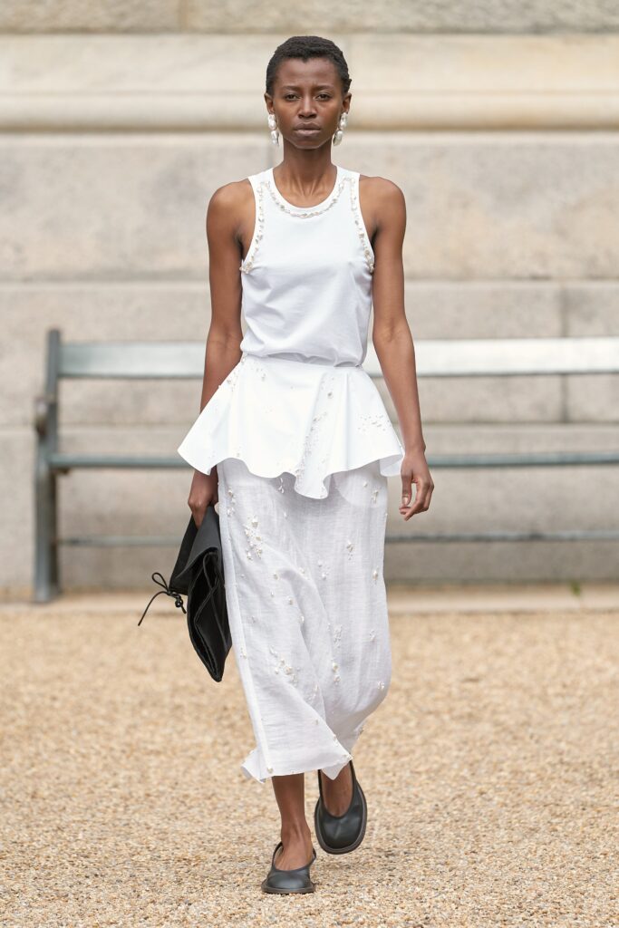 A fitted white cotton sleeveless top with a peplum design paired with a flowing maxi skirt.