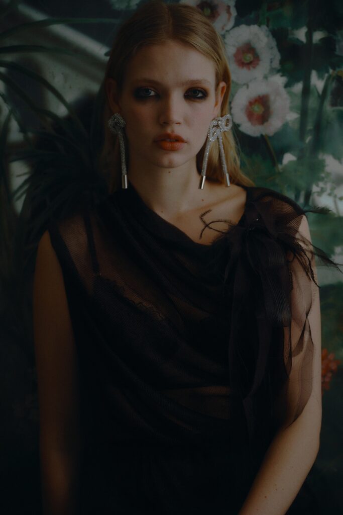 A fitted black silk dress with a sleeveless design and draped detail.