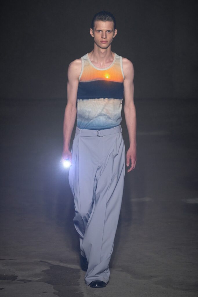 A relaxed outfit featuring gray pants and a sleeveless striped top in blue tones.