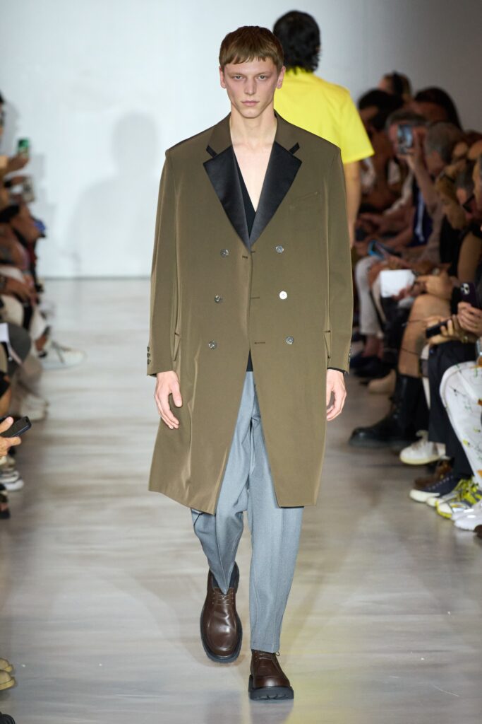 A relaxed olive wool double-breasted coat paired with gray straight-leg pants.