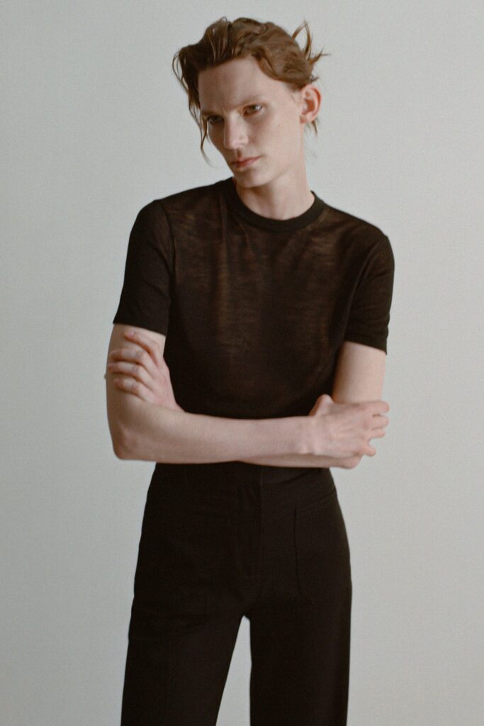 A fitted black sheer top with short sleeves paired with tailored black pants.