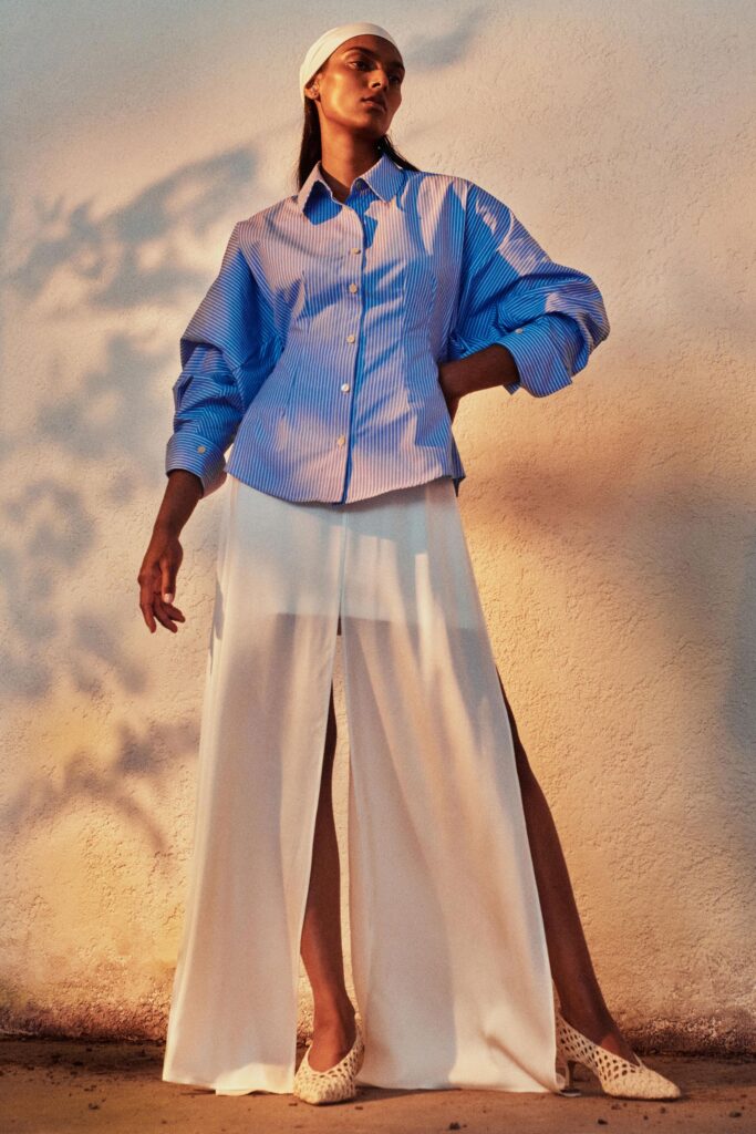 A relaxed blue striped shirt with long sleeves paired with wide-leg white pants.