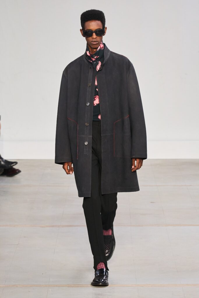 A relaxed black leather coat with long sleeves and collared design, paired with matching pants.