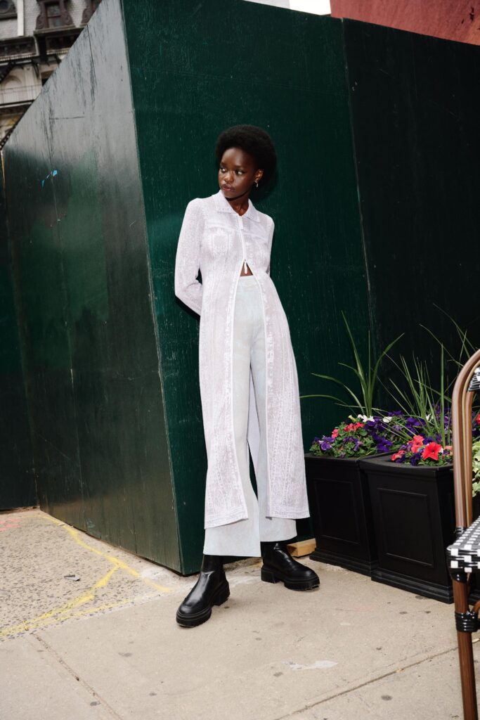 A fitted white long-sleeve collared dress paired with wide-leg pants.
