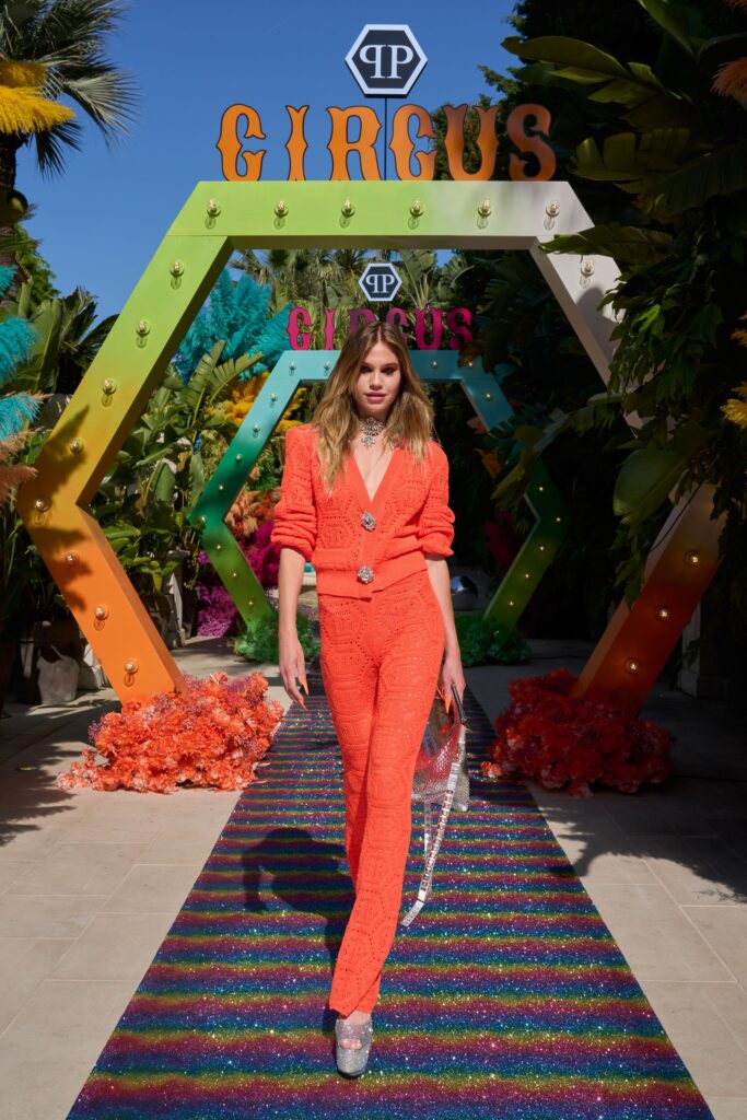A fitted orange jumpsuit with long sleeves, a V-neckline, and embroidered detailing.