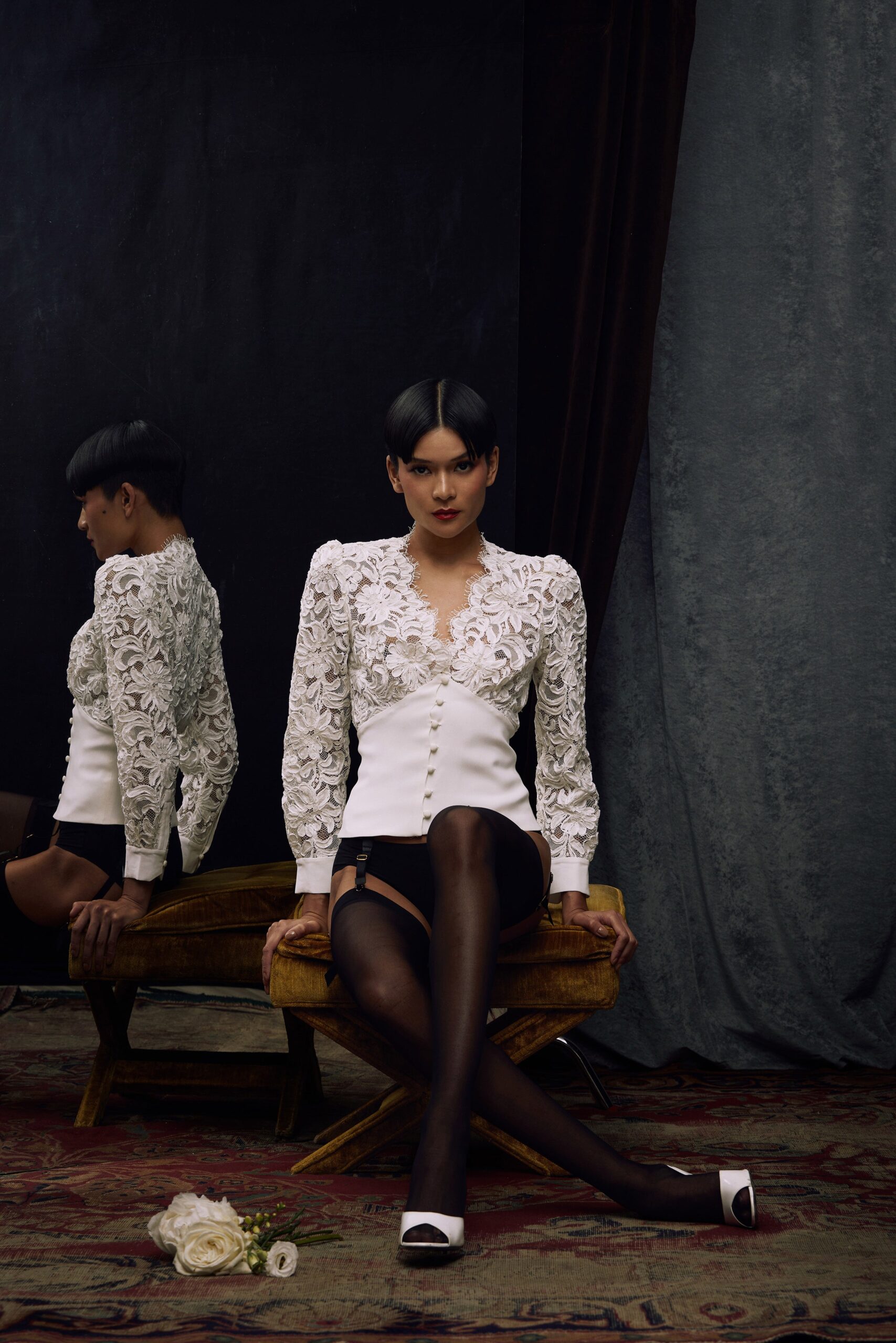A fitted white lace blouse with long sleeves, a V-neckline, and button details.