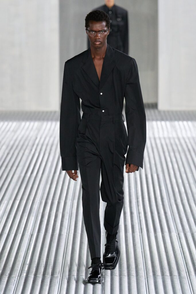 A tailored black suit with long sleeves and a collared design, featuring button details.
