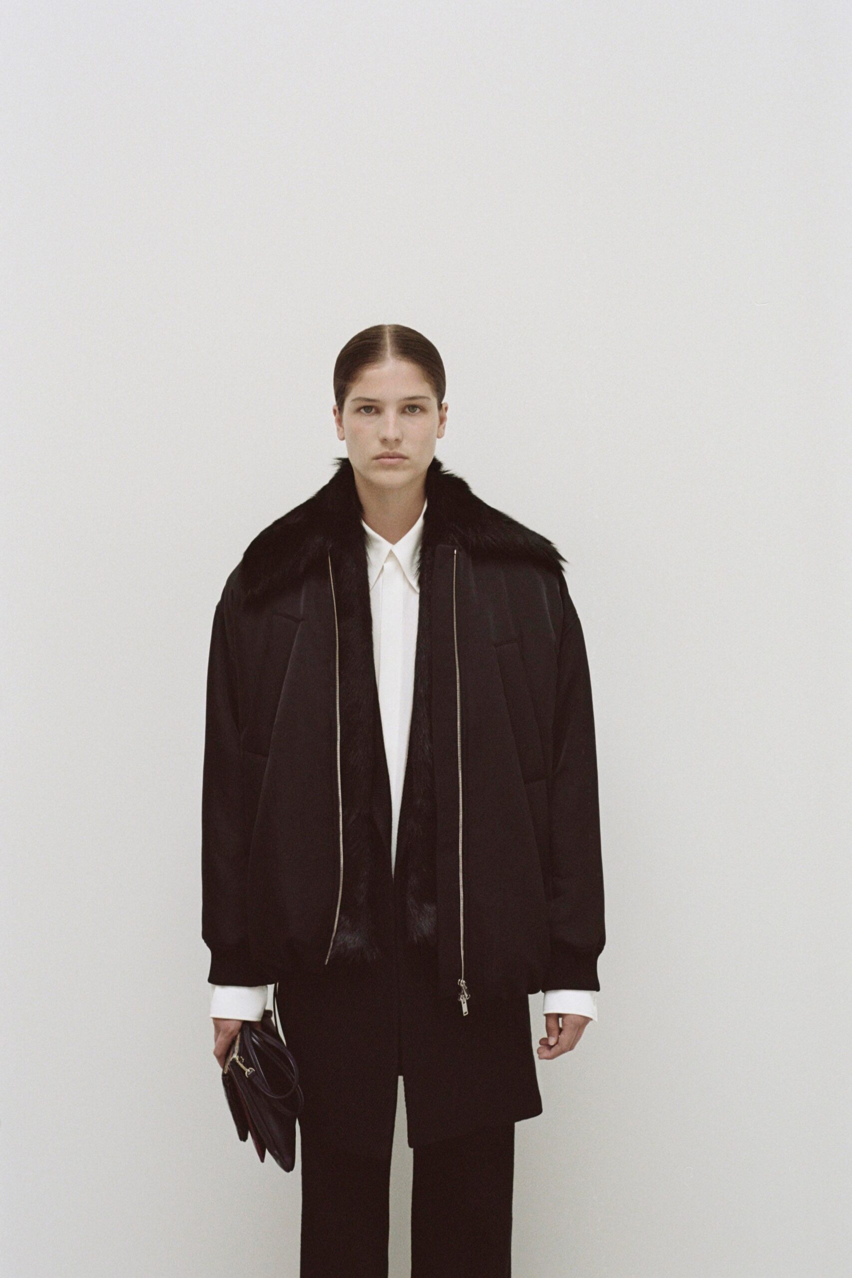 A relaxed black wool jacket with a collared long-sleeve design paired with black pants.