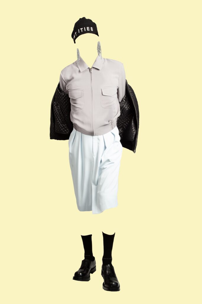 A relaxed black leather jacket paired with white pleated shorts and a collared shirt.