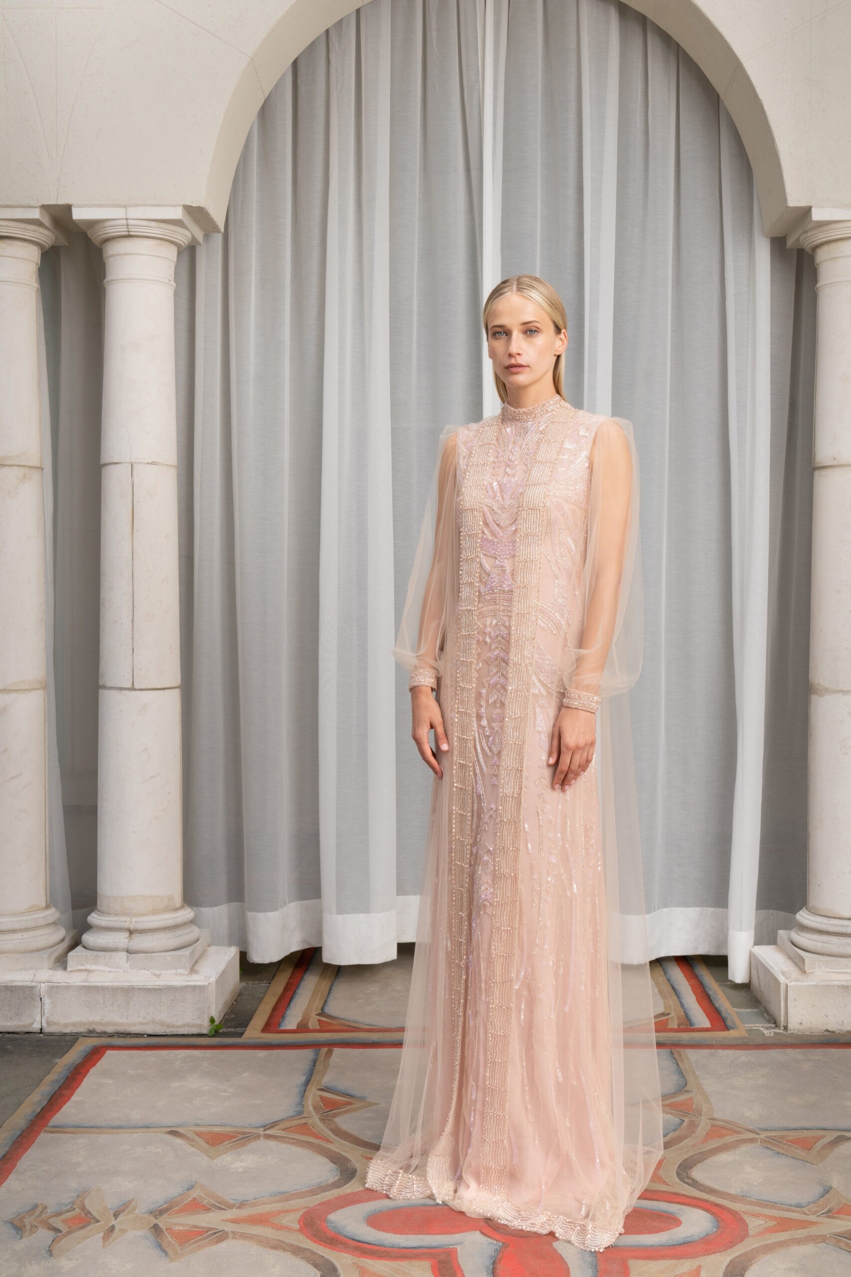 A fitted pink silk gown with long sleeves, high neckline, and intricate embroidery.